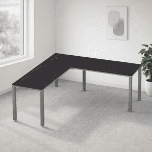 Mesa de oficina en esquina con superficie de madera oscura y estructura metálica en un espacio minim.