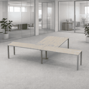 Mesa de oficina moderna en espacio de trabajo abierto con plantas y paredes de vidrio.