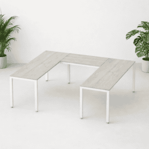 Mesa de oficina moderna en espacio minimalista con plantas verdes.